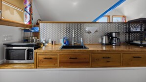 Una cucina con forno a microonde, lavello, macchina del caffè e pensili in legno.