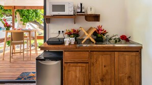 A compact kitchen with a microwave, toaster, and sink, wooden cabinets, and a small trash bin. - MATIRA BEACH RAITEA I (Bora Bora)