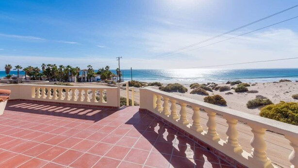 Una terrazza con vista sulla spiaggia e sull'oceano, con ringhiera e pavimento piastrellato.