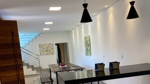 A modern interior with a dining area, a staircase, and artwork on the walls. - Cozy house. 5 km from BR 040 highway, 10 km from the shopping mall and 15 km from Lagoa Paulino lagoon. (Barreiro de Sete Lagoas)