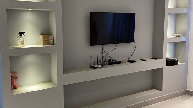 Un salon moderne doté d’étagères intégrées, d’un téléviseur à écran plat et d’un design épuré et minimaliste.