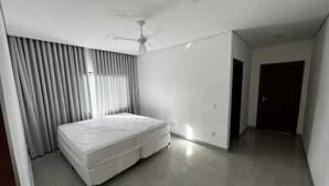 A bedroom with a bed, a ceiling fan, and a door leading to another room. - Cozy house. 5 km from BR 040 highway, 10 km from the shopping mall and 15 km from Lagoa Paulino lagoon. (Barreiro de Sete Lagoas)