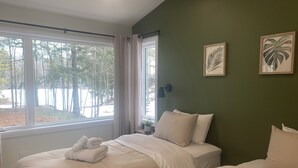 A bedroom with two beds, a window with curtains, and framed artwork on the wall. - Cozy waterfront 2-bedroom cottage in peaceful Seeley's Bay with AC (Seeley's Bay)