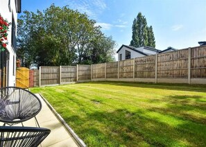 Ein Garten mit Holzzaun, Rasen und einem Stuhl.