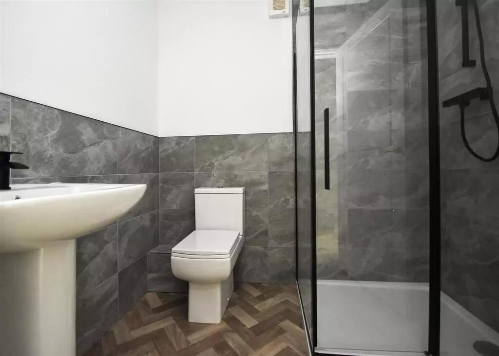 A bathroom with a white sink, toilet, and glass-enclosed shower.