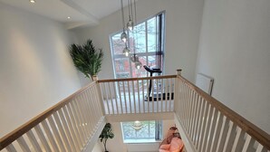 A staircase with white railings and a carpeted floor leading to a landing with a view of the outside. - Glams luxury home (Wolverhampton)