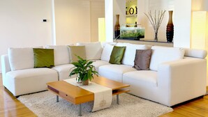 Uma sala de estar moderna com um sofá seccional, uma mesa de centro de madeira e um vaso de planta.