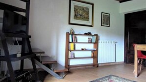 Et værelse med bogreol, et indrammet billede, en radiator og en rød stol.