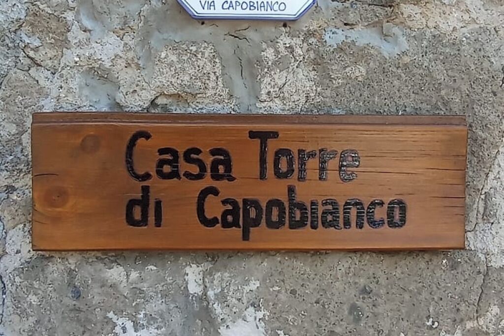 Een houten bordje met de tekst 'Casa Torre di Capobianco' erin gegraveerd.