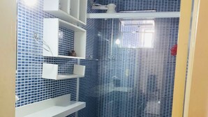 Une salle de bain avec un mur recouvert de carreaux bleus, un lavabo blanc et des toilettes avec un abattant bleu.