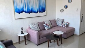 A modern living room with a sectional sofa, a coffee table, and a large abstract painting. - Entire Condo in a Gated Community with Spectacular Views  in Manzanillo, Mexico (Manzanillo)
