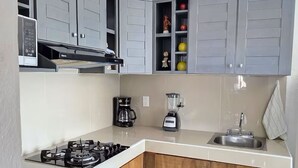 A kitchen with grey cabinets, a wooden countertop, a gas stove, a coffee maker, and a blender. - Entire Condo in a Gated Community with Spectacular Views  in Manzanillo, Mexico (Manzanillo)