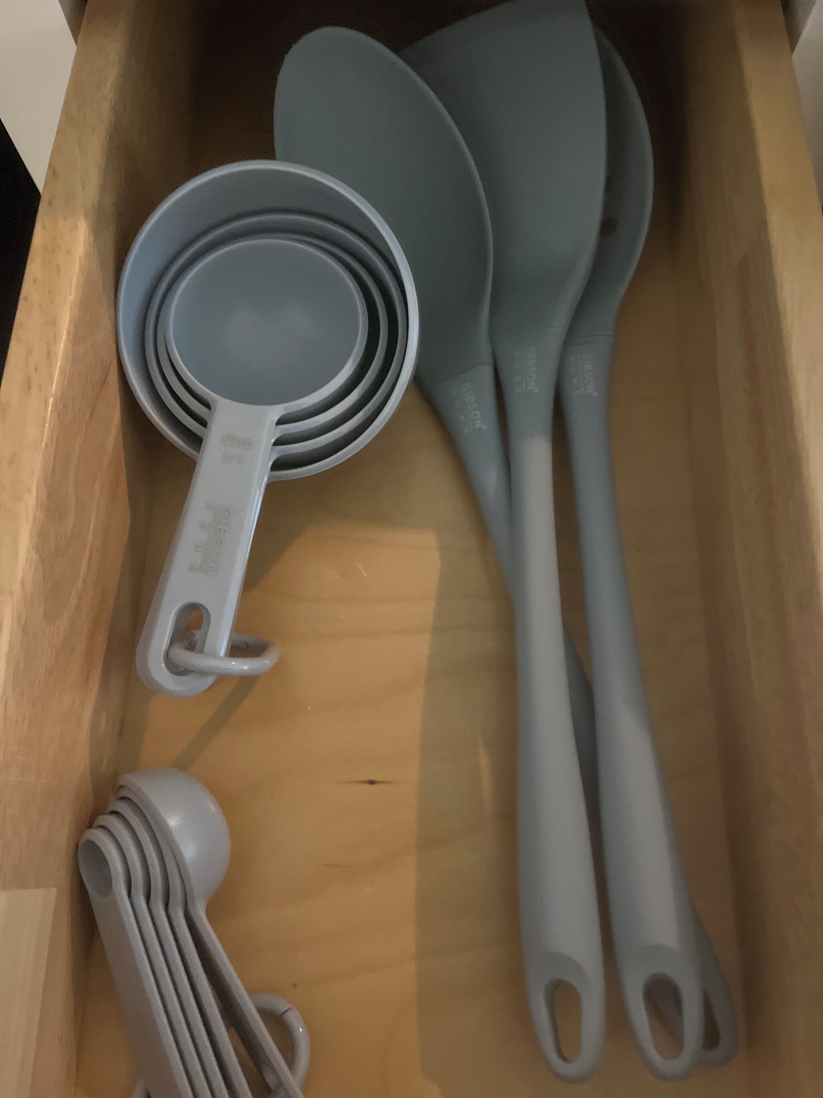 A drawer containing kitchen utensils including measuring cups and spatulas.