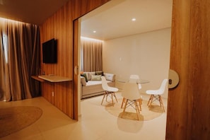 Una camera moderna con parete decorata in legno, televisione a schermo piatto, divano, tavolo da pranzo con sedie e un piccolo tappeto.