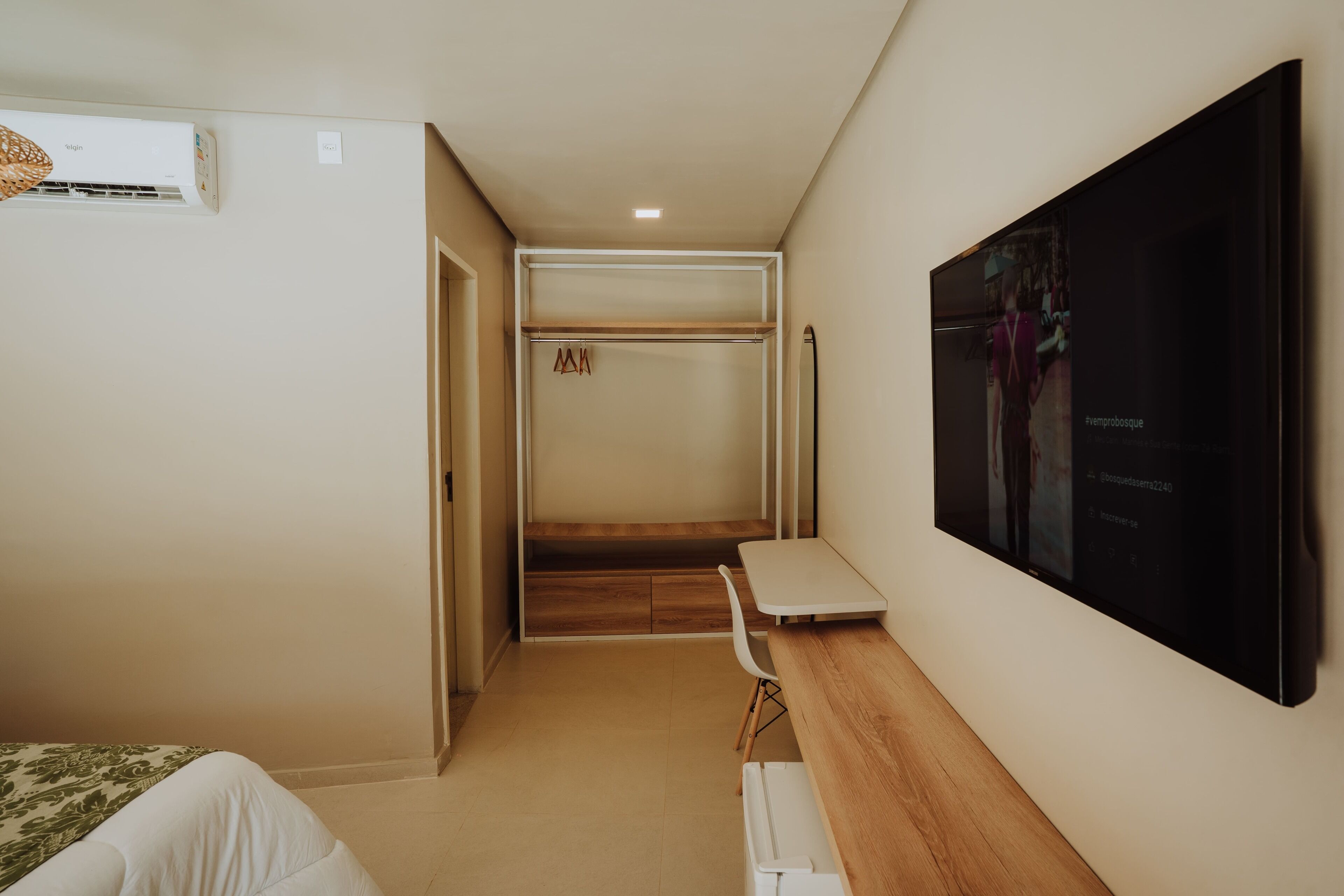 Una habitación de hotel con cama, escritorio, televisor, armario y un banco.
