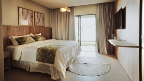 A bedroom with a bed, bedside table, curtains, a wall-mounted TV, and a view through a window. - POUSADA BOSQUE DA SERRA (Crato)