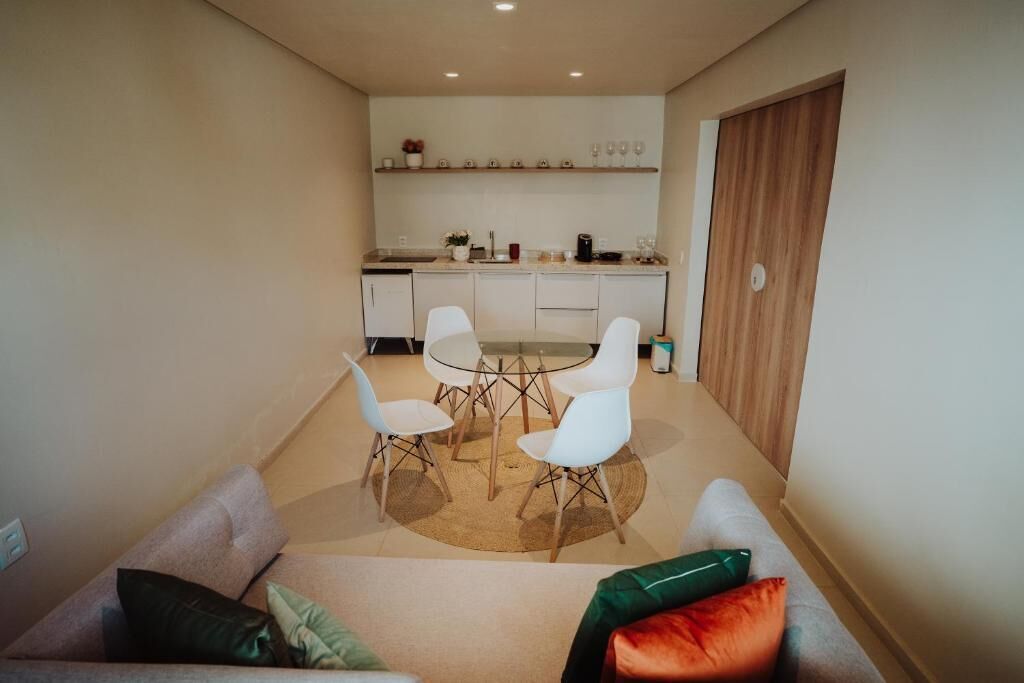 Una cocina moderna con armarios blancos, una mesa de comedor con cuatro sillas y una puerta de madera.
