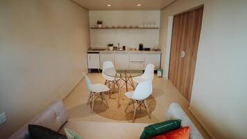 Una cocina moderna con armarios blancos, una mesa de comedor con cuatro sillas y una puerta de madera.