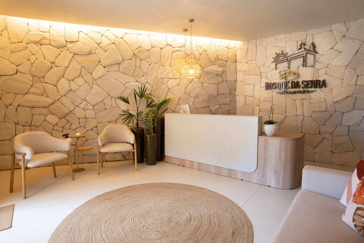 A reception area with a stone wall, a reception desk, two chairs, a round rug, and a sofa.