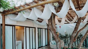 A modern outdoor patio with a wooden pergola, a hanging chair, and a small garden area with plants. - POUSADA BOSQUE DA SERRA (Crato)