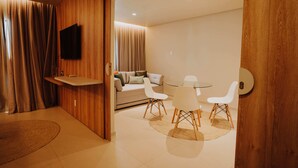 Une chambre moderne avec un mur en bois, un téléviseur à écran plat, un canapé, une table à manger avec des chaises et un petit tapis.