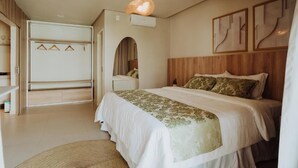 Une chambre à coucher comprenant un lit, une armoire, un luminaire suspendu et des œuvres d’art murales.