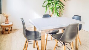 Un comedor con una mesa blanca, sillas negras y una planta verde grande.