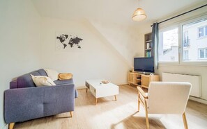 A modern living room with a sofa, a coffee table, a chair, a TV, and a world map on the wall.