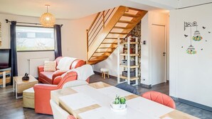 Un espacio moderno para vivir con comedor, una escalera y una pared decorativa.