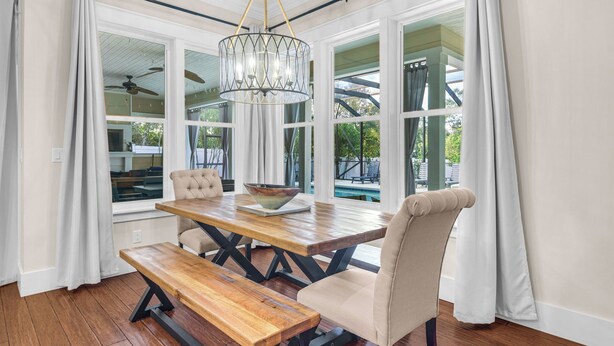 A dining area with a wooden table, cushioned chairs, a bench, and a chandelier. - 30A Getaway With Private Heated Pool, Hot Tub, and Golf Cart (Panama City Beach)