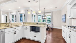 A modern kitchen with white cabinets, granite countertops, a built-in oven, and pendant lighting. - 30A Getaway With Private Heated Pool, Hot Tub, and Golf Cart (Panama City Beach)