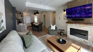 Een moderne woonkamer met een bank, salontafel, open haard en televisie.