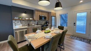 Een moderne keuken met een eethoek, roestvrijstalen apparatuur en een groot raam.