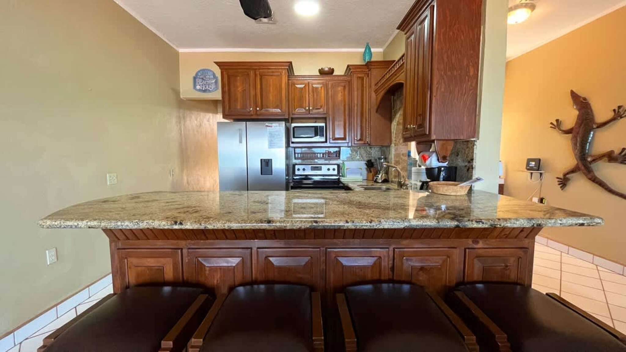 A kitchen with wooden cabinets, a granite countertop, and a built-in island with bar stools.