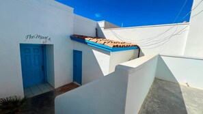 Un bâtiment blanc avec une porte bleue et une enseigne sur laquelle on peut lire : « Les 8 derniers ».