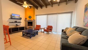Un salon avec une cheminée, un téléviseur, un canapé et un ventilateur de plafond.