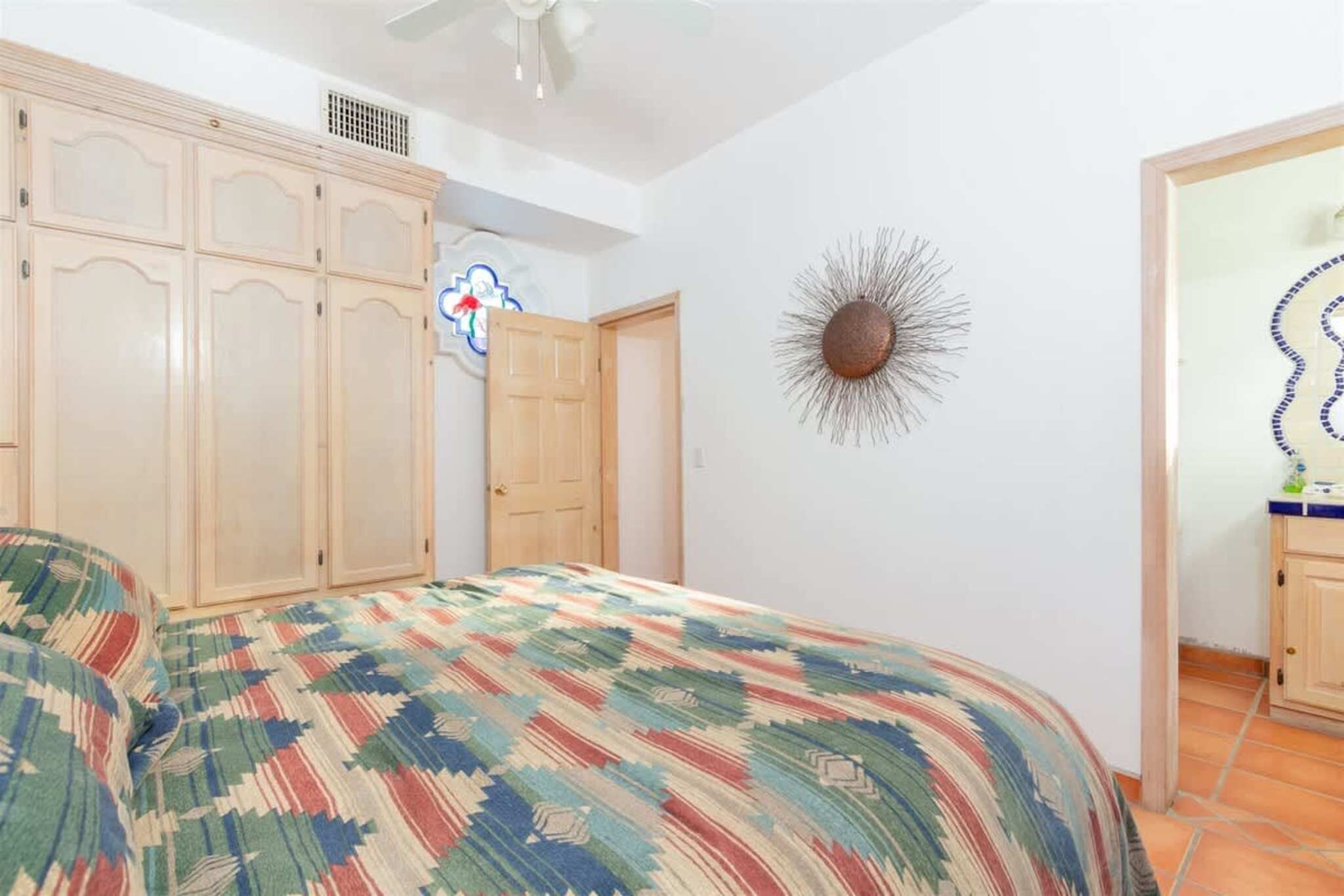 Un dormitorio con cama, armario y un adorno en la pared.