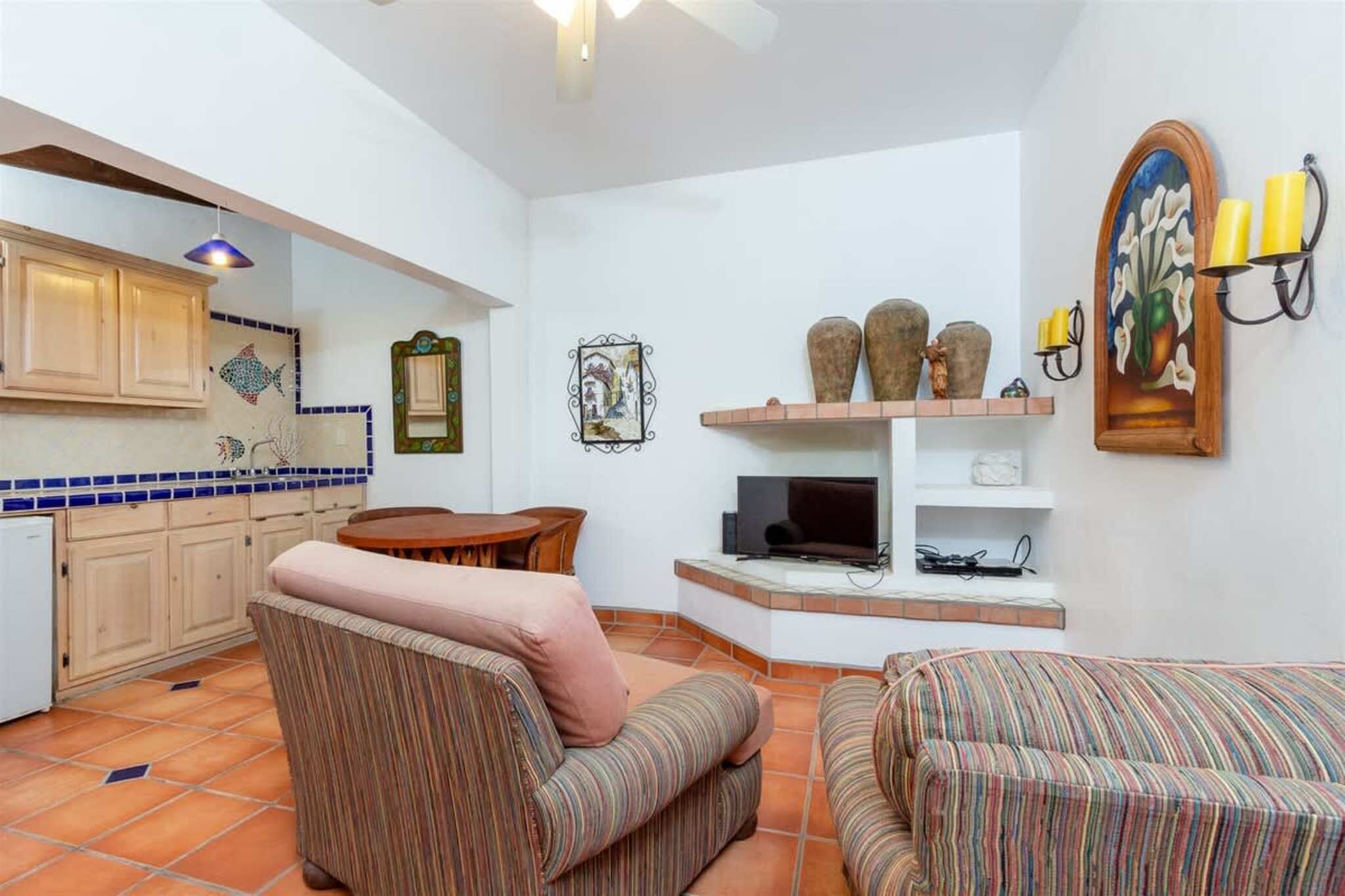 A living room with a television, a sofa, a chair, and a small table.
