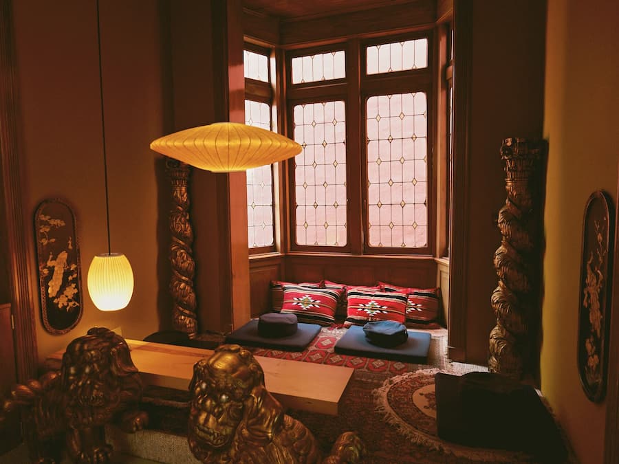 A traditional room with a wooden bench, a hanging lamp, and a window with patterned glass.