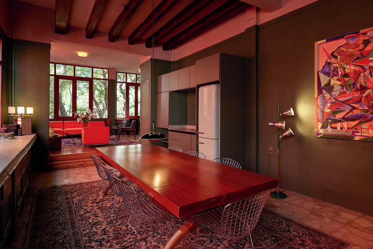 Een moderne keuken met een lange houten tafel, rode zitplaatsen en een groot raam.