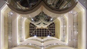Ein mehrgeschossiges Atrium mit Glasgeländern, einem offenen zentralen Bereich und einem geometrischen Deckenmuster.