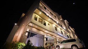 Ein mehrstöckiges Hotel mit beleuchteten Fenstern und einem gut sichtbaren Eingang.