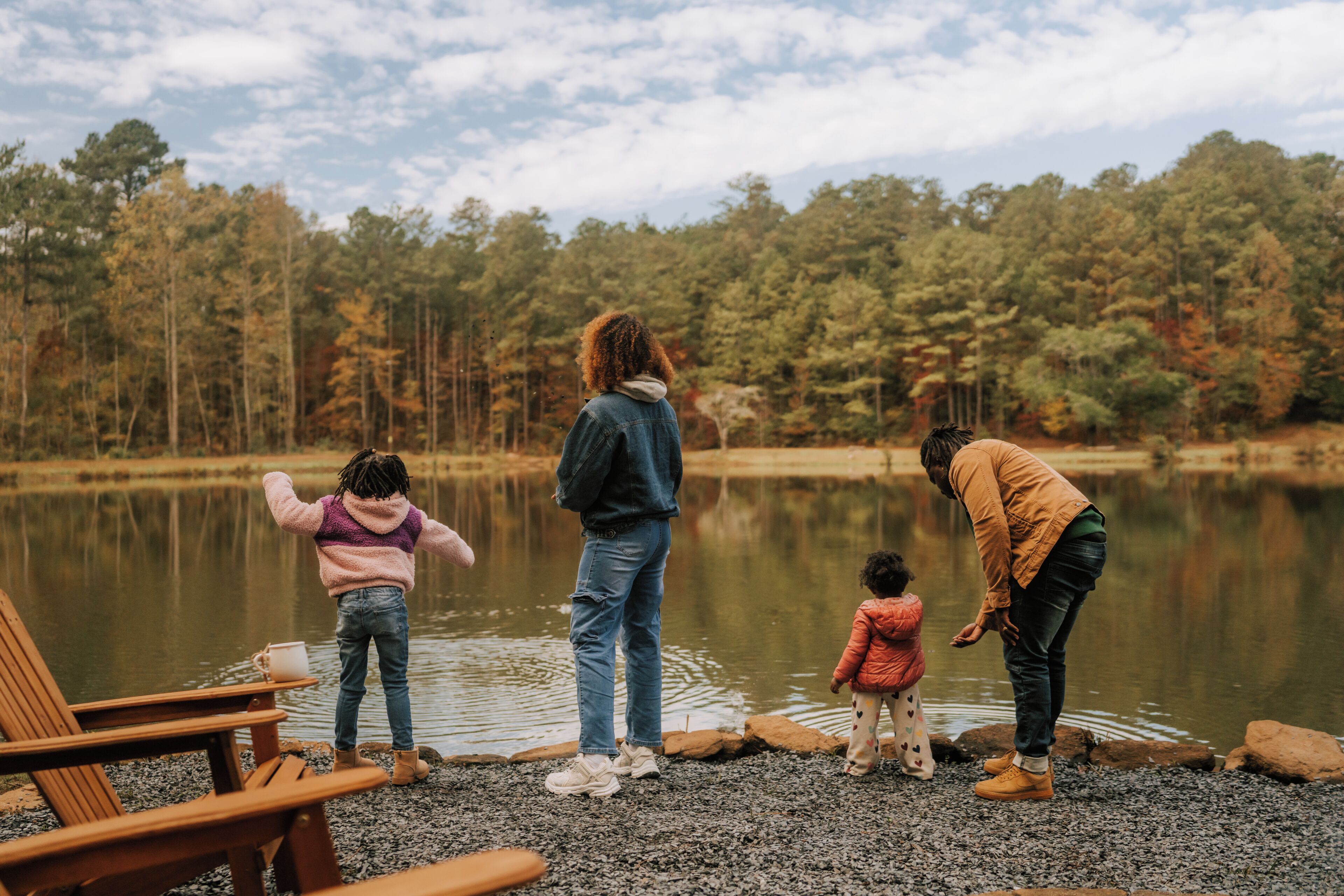 Eine Familie am See, im Hintergrund ein Wald.