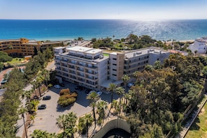 Ein mehrgeschossiges Hotel mit Dachterrasse, Parkplatz und Meerblick.