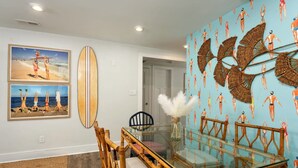 Ein Essbereich mit einem Glastisch, Holzstühlen und einer Wand mit einem Meeresblick-Mural.