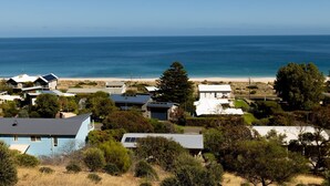 A coastal residential area with houses, a beach, and a clear view of the ocean.