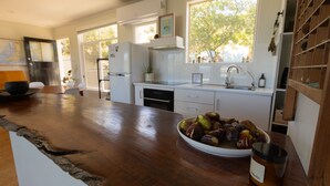 A modern kitchen with a wooden countertop, a bowl of fruit, and a coffee cup.