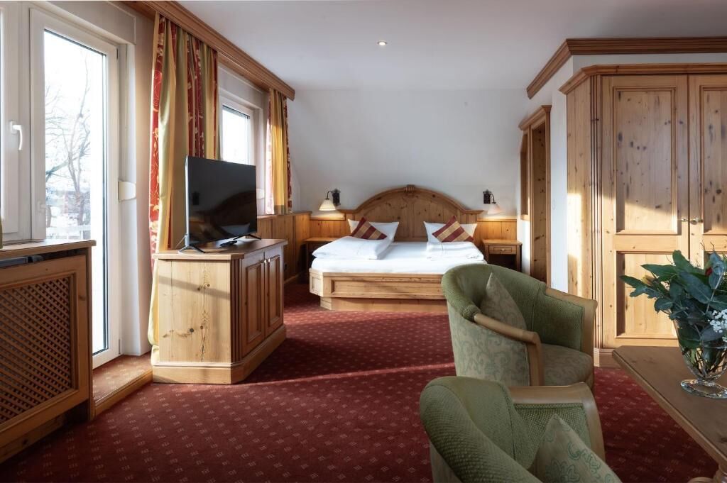 A hotel room with a bed, a desk with a television, a chair, and a cabinet.