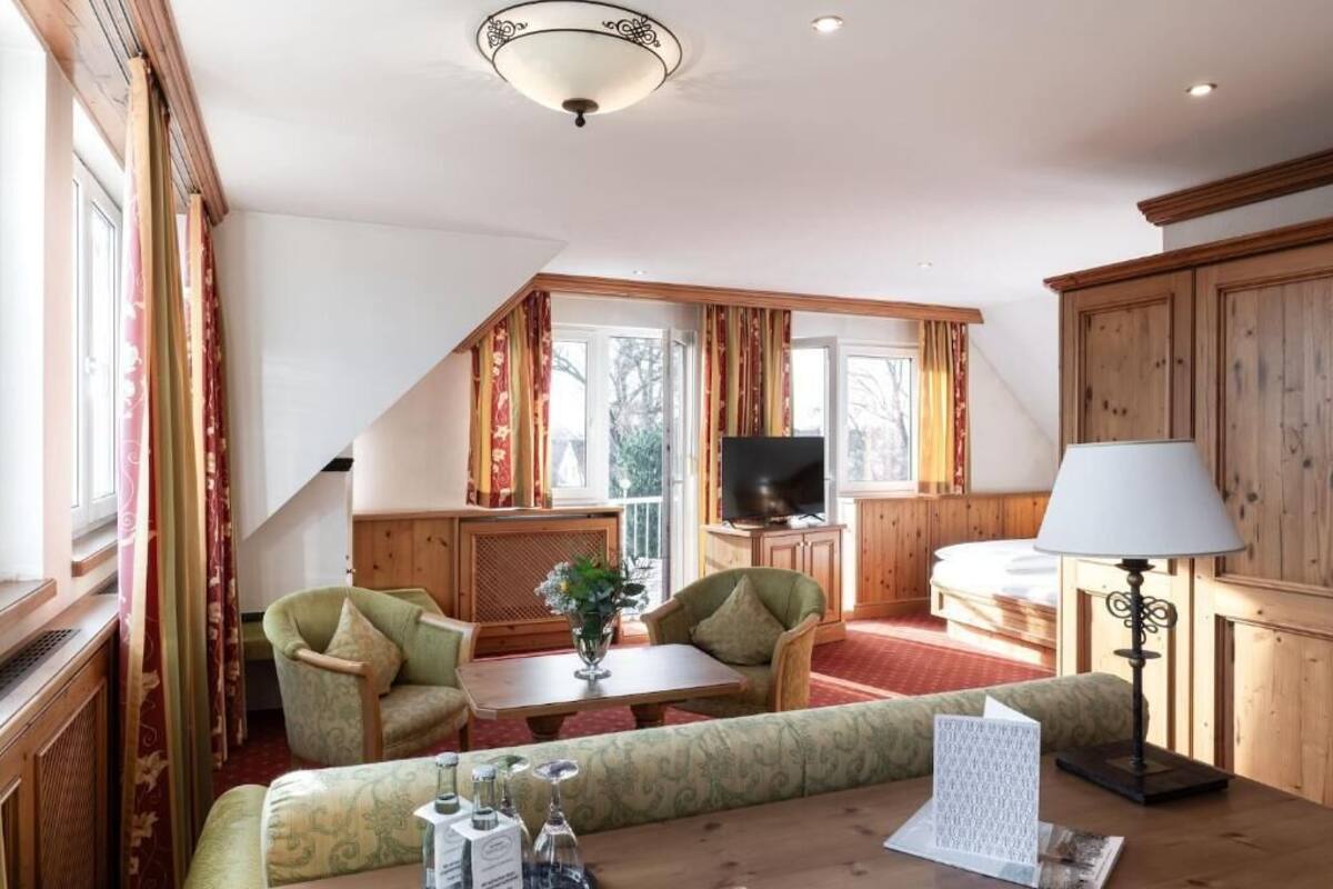 A cozy room with a sofa, chairs, a TV, and a lamp.