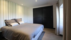 Ein Schlafzimmer mit einem Bett, einer dunklen Tür und einem Fenster mit Vorhängen.